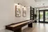 Inviting lounge area featuring elegant decor with botanical art, a modern shuffleboard table, and bright natural lighting.