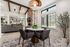 Chic open-concept living area with stylish dining set, cozy sofas, and elegant brick fireplace, flooded with natural light.