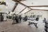 Spacious and modern gym with high ceilings, featuring state-of-the-art exercise equipment, treadmills, weights, and bright natural lighting.