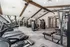 Modern gym interior with state-of-the-art fitness equipment, featuring treadmills, weight machines, and free weights under elegant wooden beam ceilings.