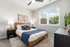 Bright and cozy bedroom featuring stylish decor, a comfortable bed with plush pillows, and large window inviting natural light.