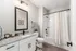 Modern bathroom featuring elegant granite countertop, sleek white cabinetry, and stylish fixtures with a cozy shower and tub area.