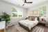 Bright and inviting bedroom with large windows, elegant decor, and a lush green view, perfect for serene living.