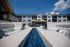 Luxurious outdoor lounge area with elegant white seating and vibrant blue glass decor, set against a modern apartment complex with balcony views and cheerful yellow umbrellas.