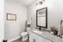 Elegant bathroom with modern fixtures, featuring a granite countertop, stylish dark-framed mirror, and tasteful decor. Inviting and bright space with contemporary touches.