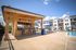 Luxurious apartment complex featuring a stylish poolside tiki bar, inviting loungers, and modern architecture, perfect for relaxation and socializing.