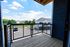 Charming balcony with wooden flooring offering a scenic view of suburban rooftops and lush greenery under a bright blue sky.