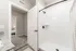 Modern bathroom with sleek granite countertops, white shower tiles, and a cozy view into a welcoming bedroom.