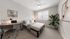 Bright and modern bedroom with a cozy bed, sleek desk setup, and vibrant green plant, enhanced by ample natural light.