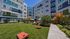 Vibrant apartment complex with colorful facades overlooking a lush green courtyard, featuring cozy outdoor seating and vibrant landscaping perfect for relaxation.