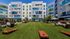 Vibrant apartment complex featuring colorful exterior, lush green lawn, and inviting outdoor seating area perfect for relaxation and social gatherings.