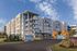 Modern apartment building, Lofts at Cascades, featuring contemporary architecture and vibrant landscaping, set against a picturesque blue sky.