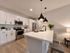 Modern kitchen with sleek white cabinetry, stainless steel appliances, and elegant pendant lighting over a spacious island with seating.