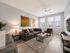 Contemporary living room with elegant decor, featuring a cozy gray sofa, artistic wall paintings, and natural light pouring through large windows.