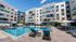 Luxurious apartment complex featuring a sparkling pool, modern lounge chairs, and vibrant architectural design.