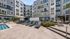 Modern apartment complex with vibrant facade featuring elegant poolside lounge area and chic seating under sun umbrellas.