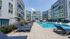 Modern apartment complex with vibrant facade and inviting outdoor pool, surrounded by ample lounging space and lush landscaping.