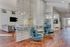 Contemporary open-concept living area featuring chic seating, stylish partition, and elegant kitchen design with sleek wood flooring.