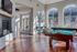 Inviting recreation room with a cozy fireplace, elegant pool table, and abundant natural light from large arched windows.