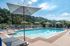 Luxurious outdoor swimming pool surrounded by lush greenery and sun loungers, perfect for relaxation and enjoying sunny days.