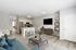 Bright open-plan living room with modern kitchen, featuring contemporary decor, sleek appliances, and a spacious island with stylish seating.