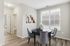 Bright dining area with a modern round table, elegant grey chairs, and large window letting in natural light.