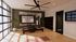 Elegant home gym with sleek mirrors, wooden floors, and abundant natural light; features modern fan, yoga mat, and lush indoor plant.