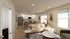 Modern open-concept living room and kitchen with inviting natural light, featuring a cozy beige sectional, elegant marble tables, and sleek kitchen cabinetry.
