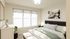 Bright and inviting bedroom with large windows, modern decor, and cozy bedding.