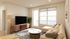 Bright living room with modern decor, featuring a cozy light beige sectional sofa, elegant marble coffee table, and large window overlooking a scenic view.