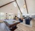 Elegant apartment common area featuring a stylish billiards table, plush seating arrangement, and modern decor under a vaulted ceiling with natural light.