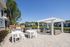 Inviting outdoor patio with white pergola, cozy lounge seating, and sleek barbecue area overlooking lush greenery.
