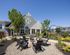 Charming outdoor lounge area featuring stylish Adirondack chairs, vibrant landscaping, and a modern building backdrop.