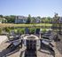 Serene outdoor patio with Adirondack chairs surrounding a fire pit, overlooking a picturesque pond and lush greenery.