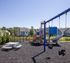 Inviting playground with swings, slide, and picnic area set against a backdrop of charming residential homes.