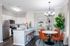 Modern kitchen and dining area with sleek stainless steel appliances, elegant marble countertops, and stylish leather chairs, complemented by vibrant greenery and chic decor.