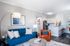 Chic and modern living room featuring a plush blue sofa, a cozy leather chair, and a stylish open kitchen with granite countertops.
