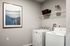 Chic laundry room with modern washer and dryer, elegant artwork, and efficient shelving.