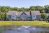 Charming suburban townhouses by a serene pond with a fountain, surrounded by lush greenery and inviting outdoor spaces.