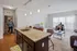 Modern open-plan living space with a sleek granite kitchen island, comfortable seating area, and abundant natural light pouring through large windows.