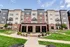 Modern apartment building with elegant brick and panel facade, featuring spacious balconies and a beautifully landscaped lawn with seating areas.