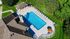 Luxurious aerial view of private pool with sun loungers and umbrellas, surrounded by lush greenery and a stylish cabana.