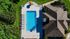 Aerial view of a luxurious backyard featuring a sparkling blue swimming pool, surrounded by lush greenery and stylish lounge chairs.
