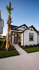Charming modern home with a welcoming entrance, elegant palm tree, and lush green landscaping.