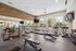 Bright and modern fitness center with treadmills, strength machines, and free weights, featuring large windows for natural light and a sleek brick accent wall.