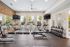Contemporary fitness center with state-of-the-art treadmills, weight racks, and wall-mounted TVs, offering a vibrant workout space with natural light.