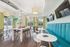 Bright and modern community room with sleek furniture, large windows, vibrant teal seating, and a ping-pong table for leisure activities.
