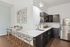 Modern kitchen featuring sleek dark cabinetry, elegant marble countertops, and stylish bar seating in a bright, contemporary space.