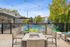 Chic outdoor patio with cozy seating, a fire pit, and string lights overlooking a refreshing pool, framed by modern architecture and lush greenery.