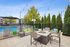 Chic outdoor lounge area with cozy seating and stylish fire pit, overlooking a sparkling blue pool and lush greenery, offering a perfect relaxation spot.